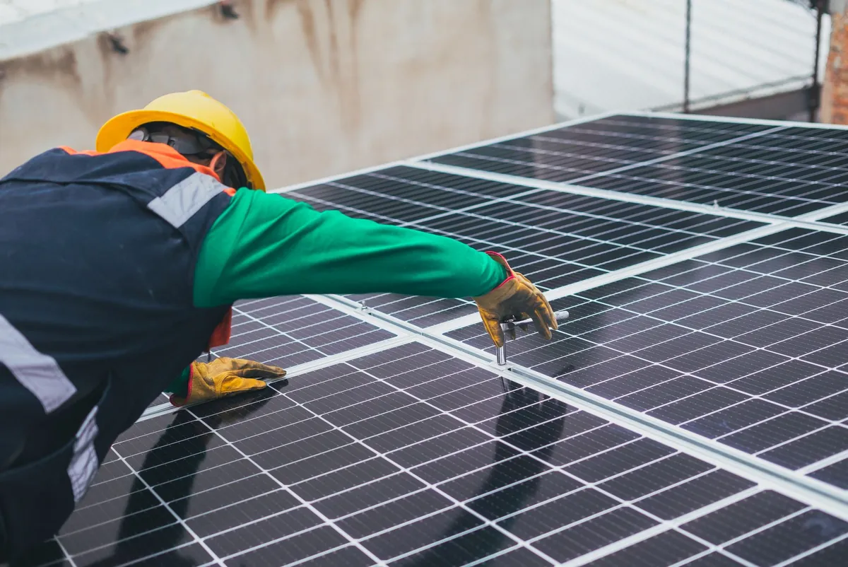Tehnician instalând un panou fotovoltaic pe acoperiș